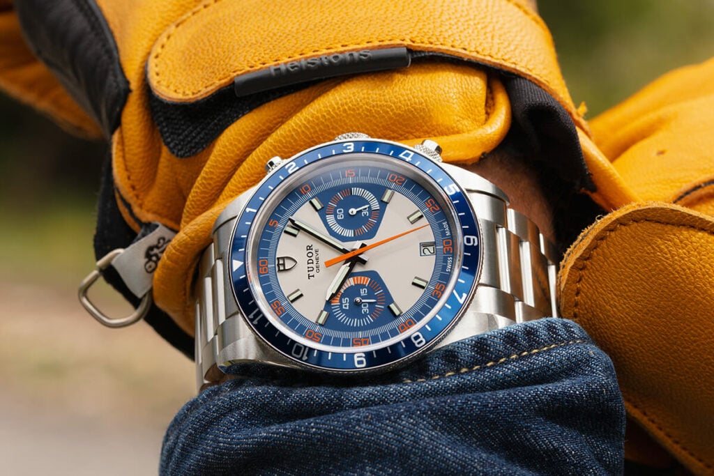 Tudor Heritage Chrono Blue com bracelete em aço num pulso com uma luva amarela