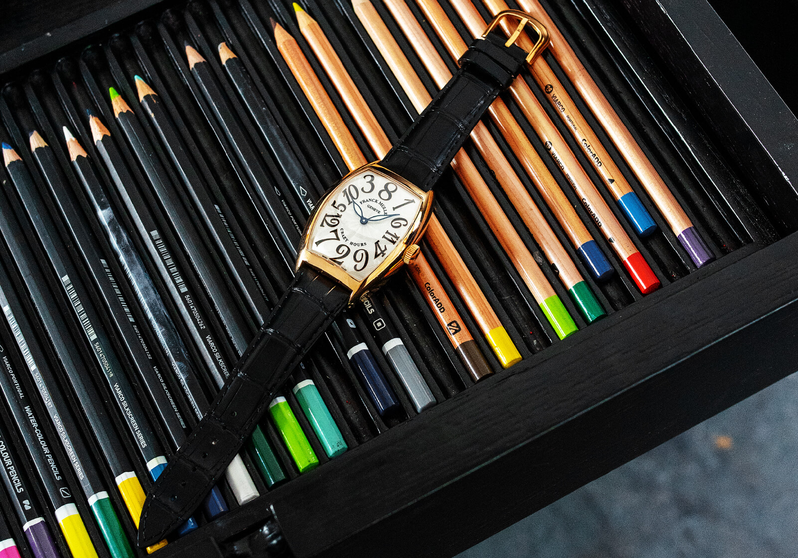 Franck Muller Cintrée Curvex Crazy Hours em cima de uma caixa de lápis da Viarco