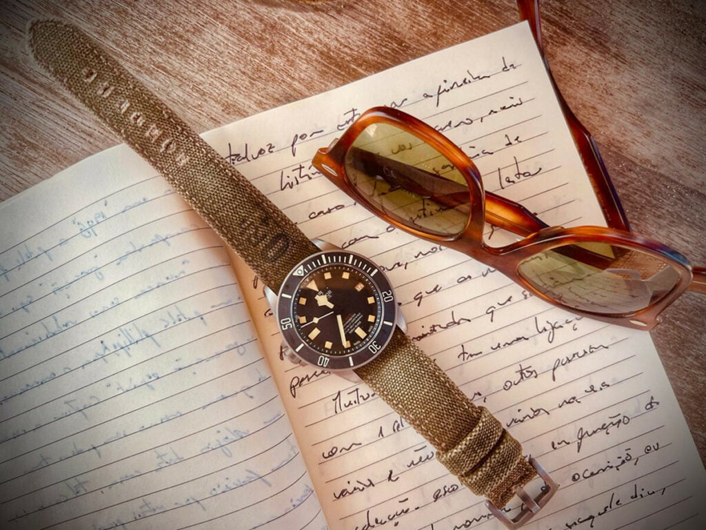 Relógio Tudor sobre um caderno de notas, junto a um par de óculos