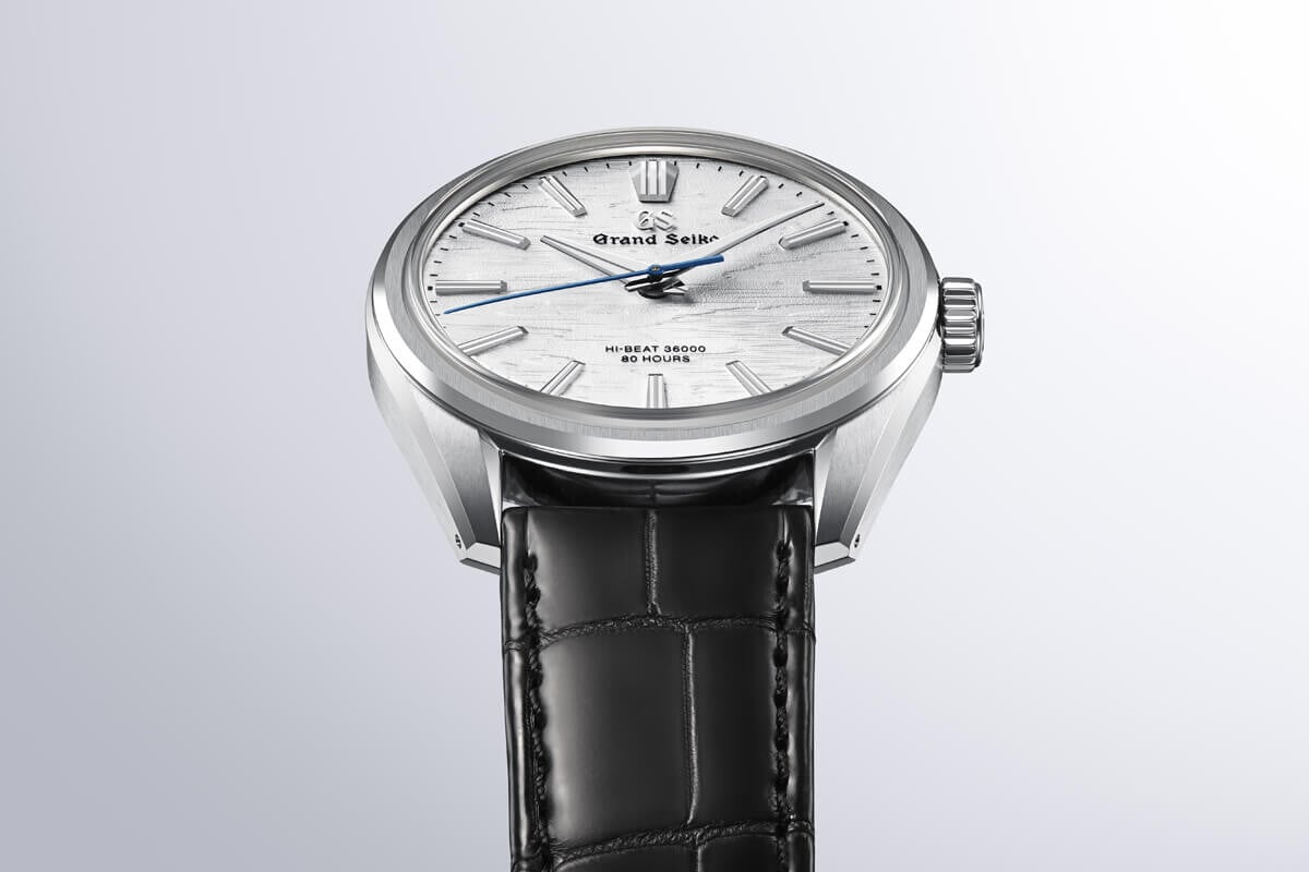 Relógio Grand Seiko visto em posição 'cobra' com mostrador branco texturado e correia preta