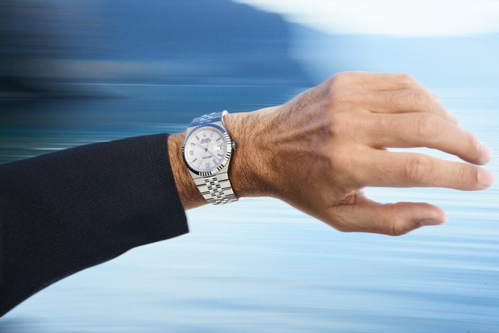 Imagem de uma mão e parte de um braço masculino com um Rolex Land-Dweller no pulso