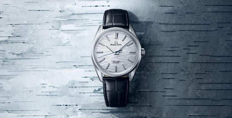 Relógio Grand Seiko SLGW003 visto de frente com mostrador branco texturado, caixa prateada e correia preta em pele de aligátor.