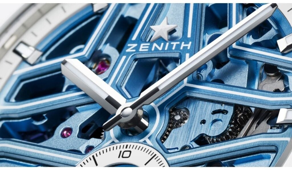 Close-up do movimento interno azul do Zenith DEFY Skyline Skeleton White Ceramic e detalhe do mostrador com ponteiros prateados e elementos mecânicos visíveis.