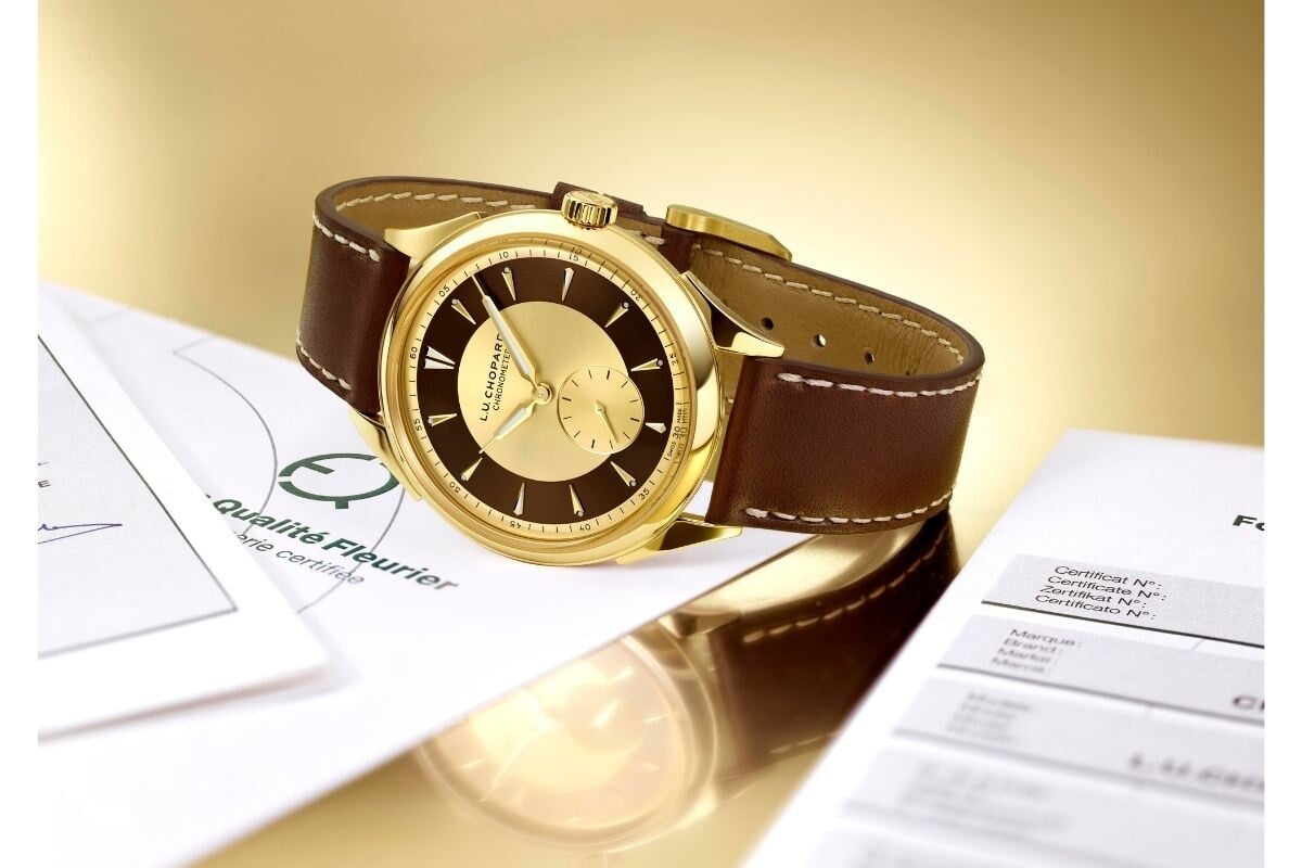 relógio de pulso L.U.C Qualité Fleurier 20th Anniversary Edition em tons dourados deitado sobre um papel alusivo à certificação Qualité Fleurier