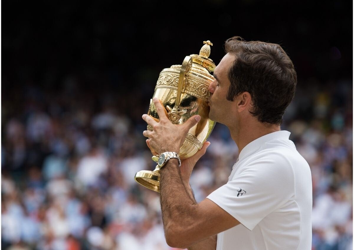 Roger Federer beija o troféu de Wimbledon usando um relógio Rolex no pulso.