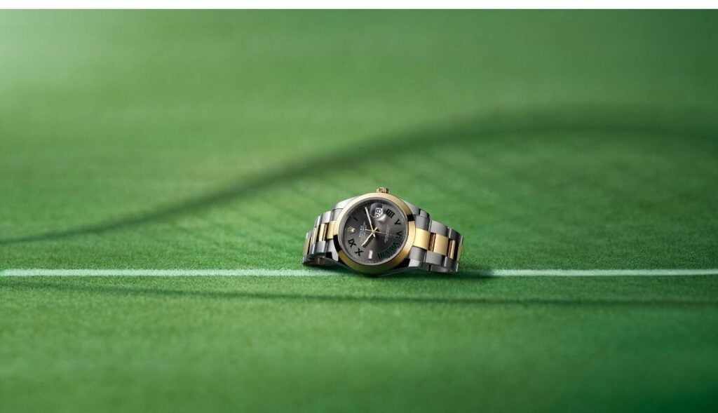 Relógio Rolex Datejust com mostrador wimbledon cinzento fotografado num court de ténis