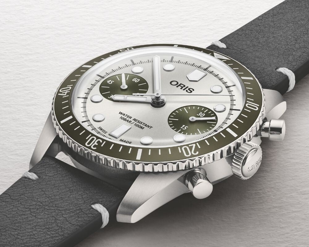 Close lateral do relógio Oris Divers Sixty-Five Chronograph destacando a coroa, botões e luneta rotativa verde.