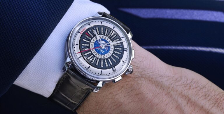 Relógio Bovet Récital 30 Worldtimer no pulso de um homem com casaco azul, destacando o mostrador com múltiplos fusos horários.