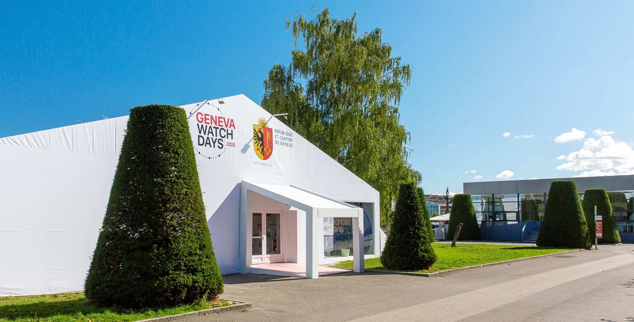 Estrutura branca com logotipo do Geneva Watch Days 2025 e brasão de Genebra, servindo como entrada principal do evento.