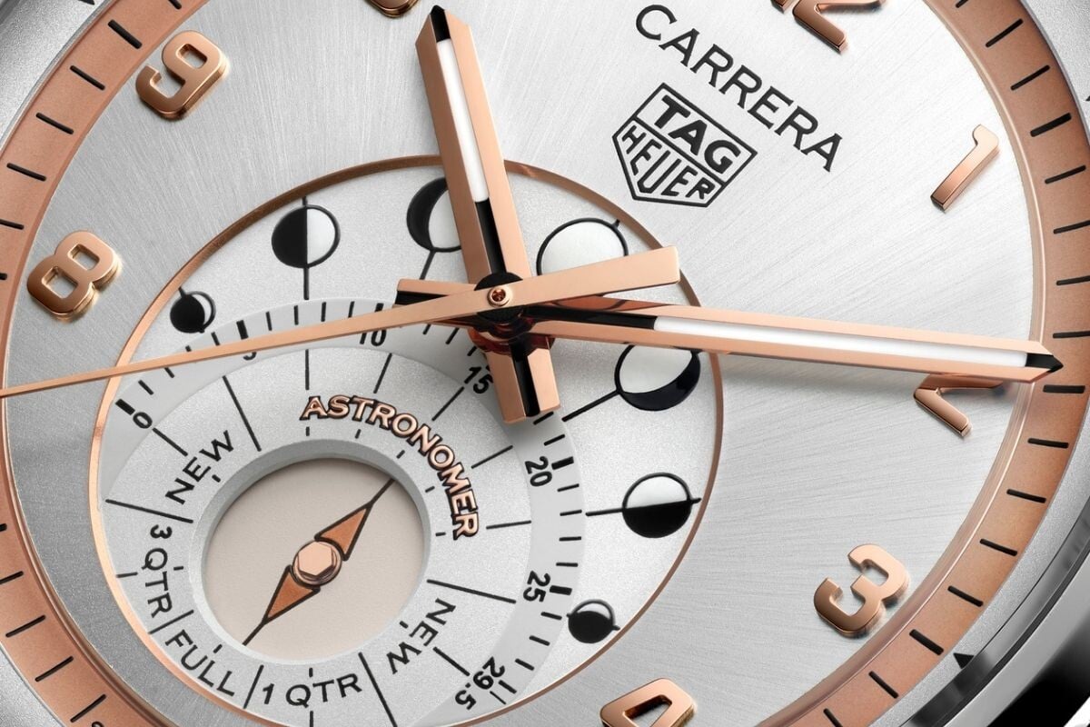 Close-up do mostrador do relógio TAG Heuer Carrera Astronomer com indicador de fases da lua e ponteiros em ouro rosa.