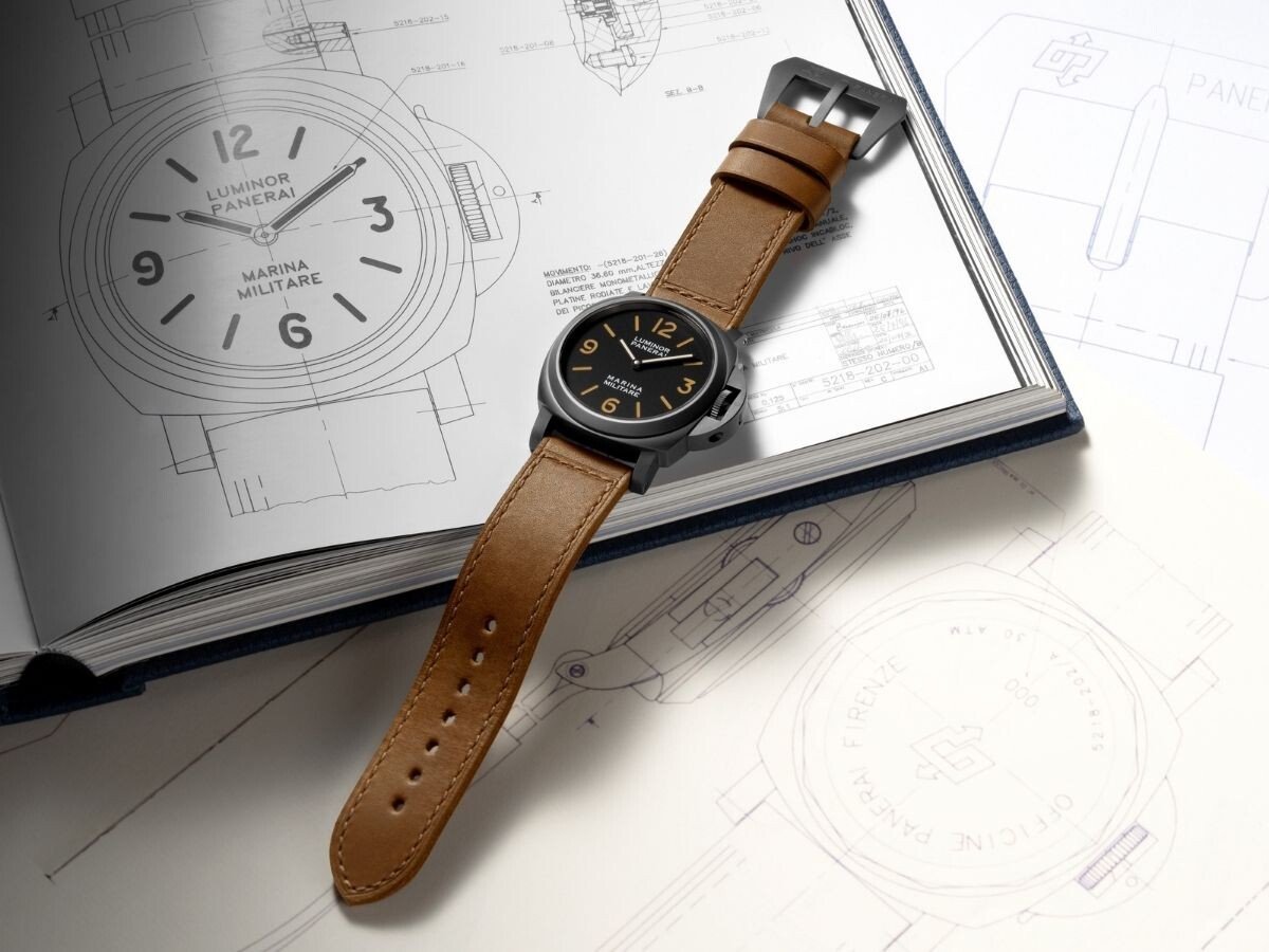 Relógio Panerai Luminor Marina Militare com bracelete em couro castanho sobre livro com desenhos técnicos do modelo.