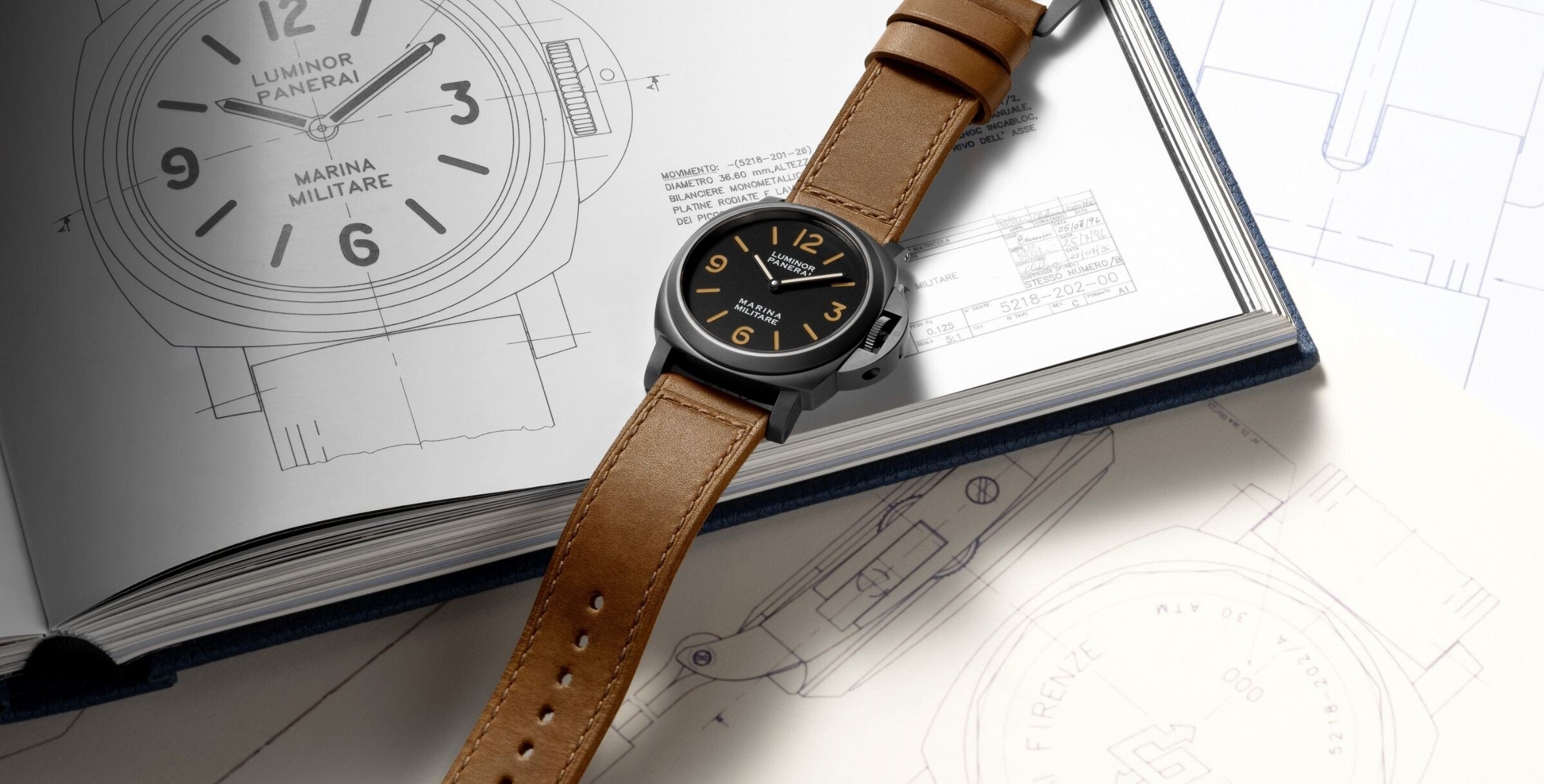 Relógio Panerai Luminor Marina Militare com bracelete em couro castanho sobre livro com desenhos técnicos do modelo.