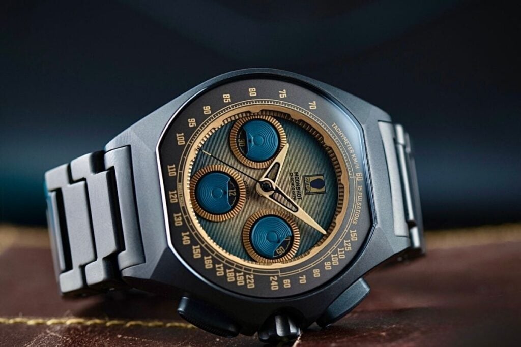 relógio em titânio preto com mostrador castanho e azul e bracelete em titânio em cima de uma mesa Isotope Chronograph Moonshot Terra Maris