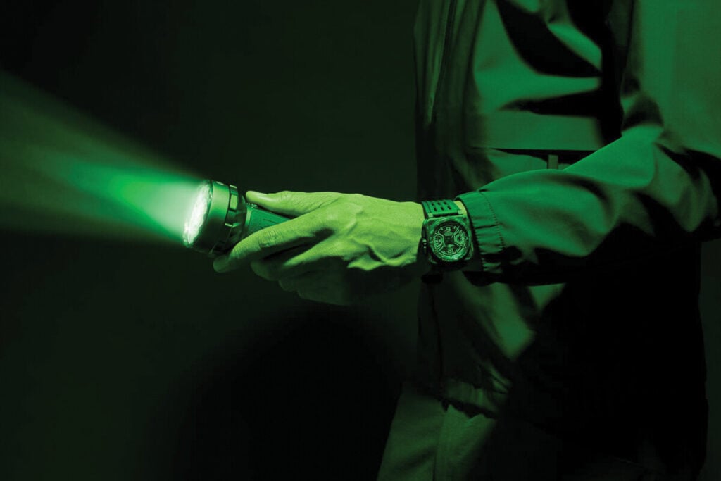 Relógio Bell & Ross BR-X3 Night Vision com mostrador preto e detalhes luminosos em verde, caixa quadrada de carbono e bracelete em borracha preta.