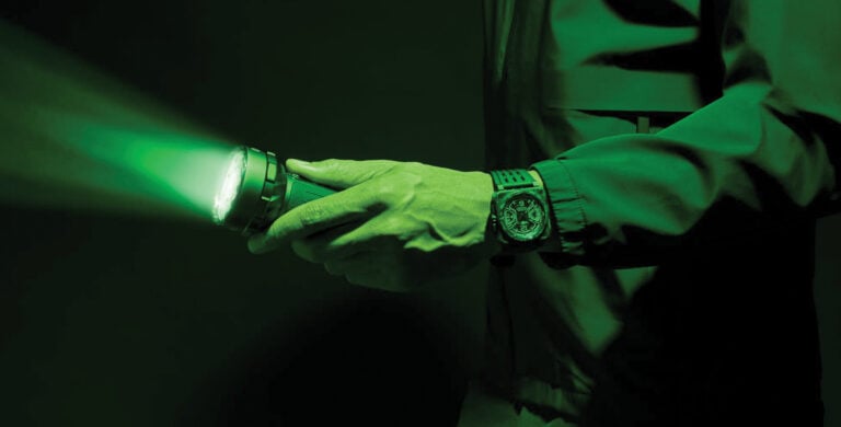 Relógio Bell & Ross BR-X3 Night Vision com mostrador preto e detalhes luminosos em verde, caixa quadrada de carbono e bracelete em borracha preta.