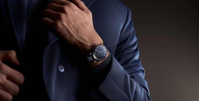 Frederique Constant Classic Perpetual Calendar Manufacture de mostrador azul escuro visto no pulso de um homem vestido com fato azul, num plano aproximado