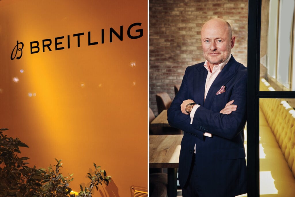 homem de braços cruzados na boutique Breitling com relógio Breitling de ouro no pulso e lenço no casaco