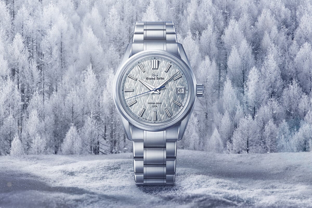 Relógio de pulso prateado com mostrador texturizado em tom claro e ponteiro dos segundos azul.