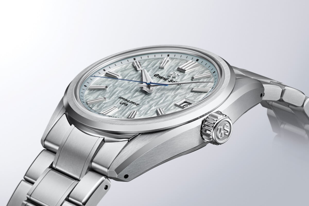 Relógio de pulso prateado com mostrador texturizado em tom claro e ponteiro dos segundos azul.