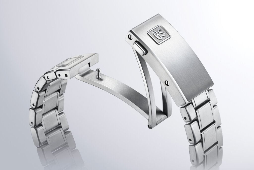 Fecho de aço inoxidável de um relógio Grand Seiko com bracelete de metal.