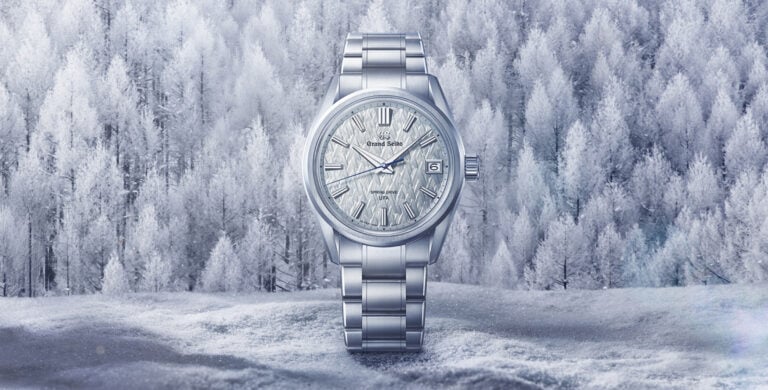 Relógio de pulso prateado com mostrador texturizado em tom claro e ponteiro dos segundos azul.