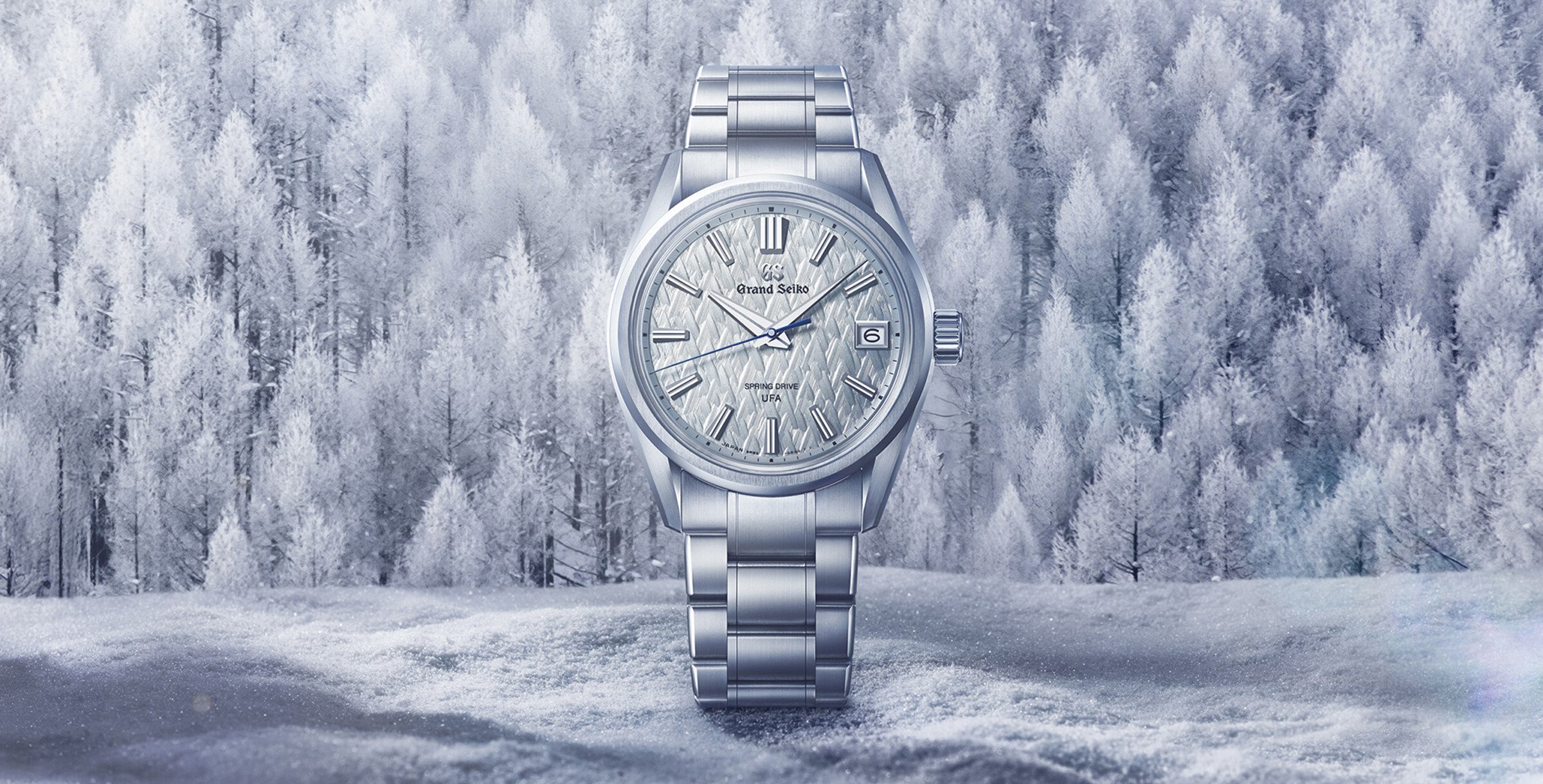 Relógio de pulso prateado com mostrador texturizado em tom claro e ponteiro dos segundos azul.