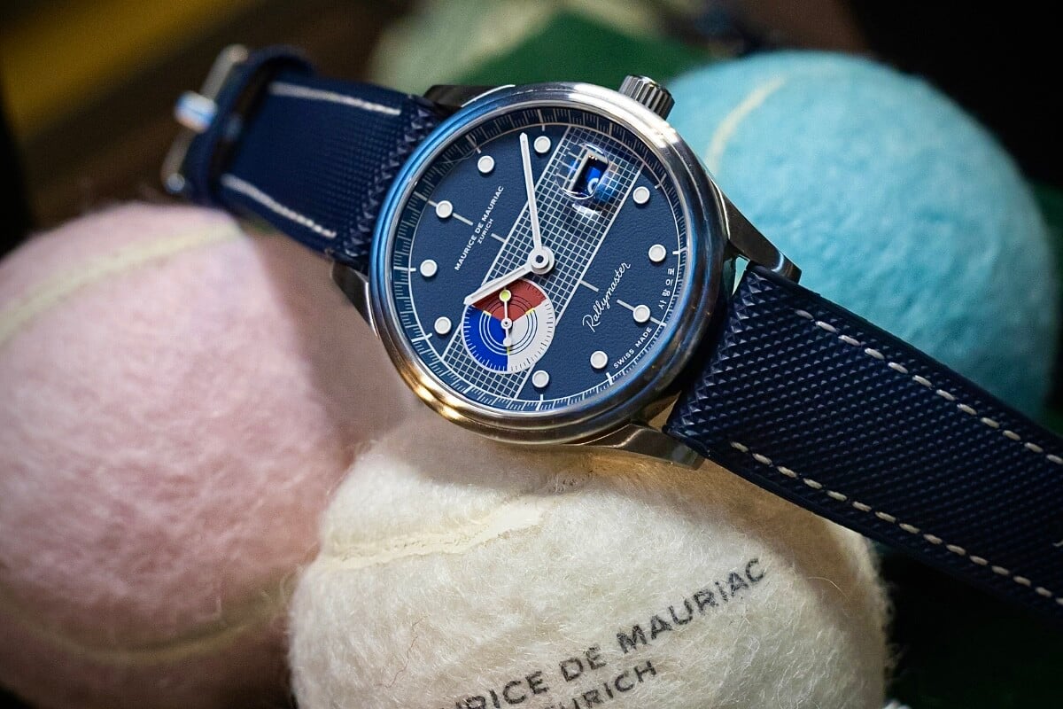relógio azul com pormenores vermelhos e bracelete azul em cima de bolas de ténis de cor branca, rosa e azul, marca Maurice de Mauriac, modelo Rallymaster Korean Open