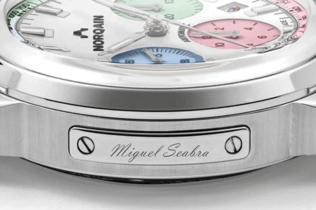 Rel&oacute;gio autom&aacute;tico Norqain Freedom 60 40mm Enjoy Life Special Edition em a&ccedil;o inoxid&aacute;vel, com cron&oacute;grafo e mostrador branco com submostradores coloridos em azul, verde e rosa, gelado na data com placa lateral com inscri&ccedil;&atilde;o Miguel Seabra