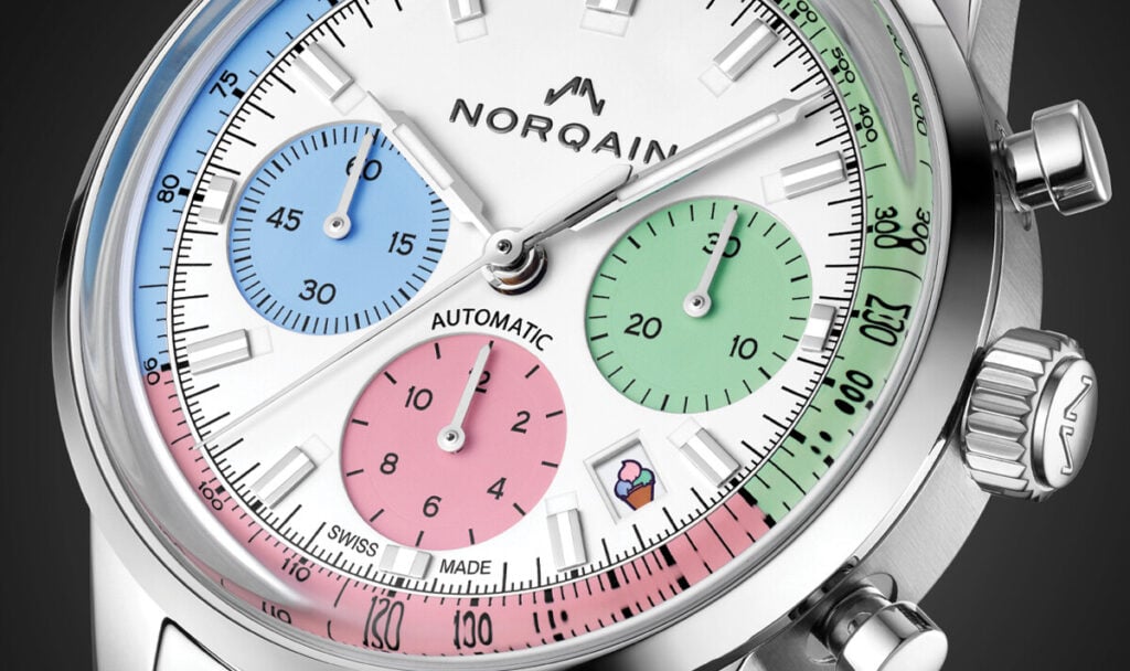 Detalhe de um rel&oacute;gio cron&oacute;grafo NORQAIN com mostrador branco e submostradores em tons pastel azul, verde e rosa.