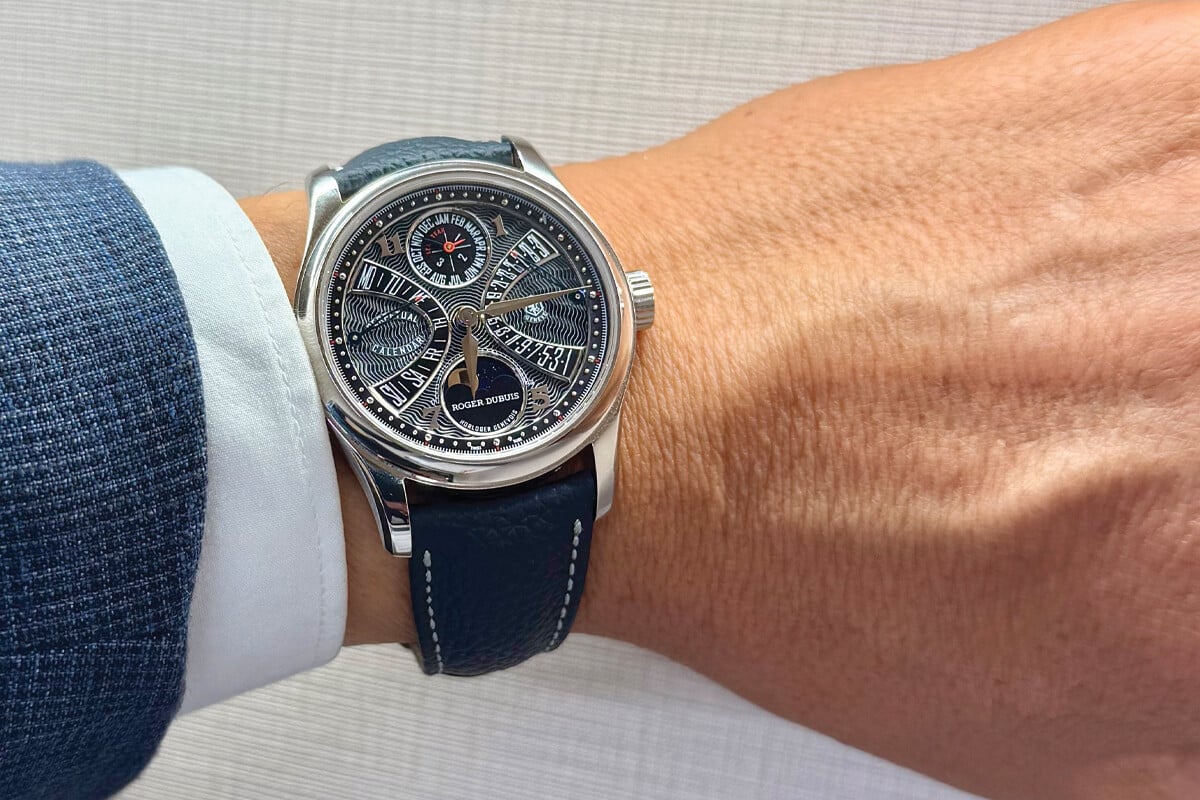 Rel&oacute;gio de luxo da marca Roger Dubuis em um pulso masculino, com mostrador detalhado e pulseira de couro azul.