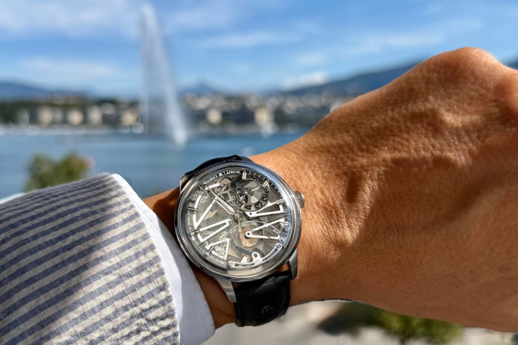 Rel&oacute;gio Maurice Lacroix com mostrador esquel&eacute;tico vis&iacute;vel no pulso de uma pessoa. O rel&oacute;gio est&aacute; em posi&ccedil;&atilde;o de destaque, com os detalhes das engrenagens, o n&uacute;mero 03 na data e os dias da semana vis&iacute;veis. A caixa de a&ccedil;o inoxid&aacute;vel e a pulseira de couro preto complementam o design elegante.