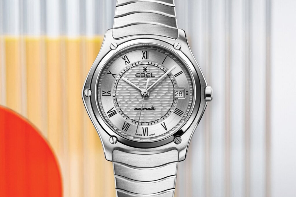 Rel&oacute;gio Ebel Sport Classic em a&ccedil;o inoxid&aacute;vel, com mostrador prateado texturizado, numerais romanos e pulseira met&aacute;lica integrada.