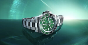 Relógio Rolex GMT-Master II em aço, com mostrador verde e luneta bicolor preta e verde, visto de perfil sobre fundo verde luminoso.