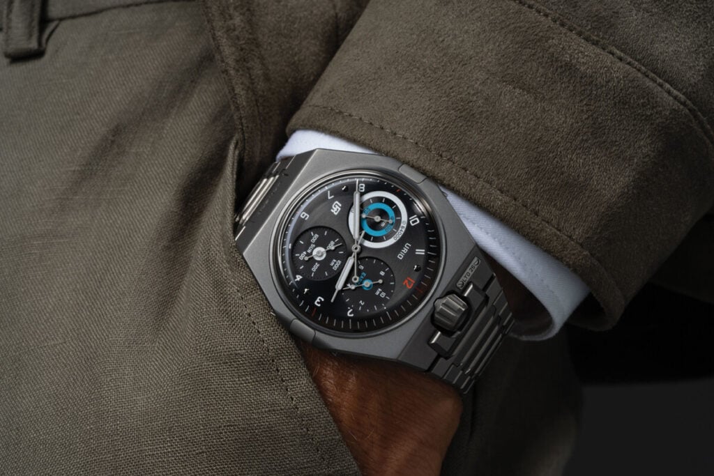 &ldquo;Rel&oacute;gio de luxo Urwerk no pulso, com caixa e pulseira met&aacute;licas e mostrador escuro com submostradores t&eacute;cnicos.