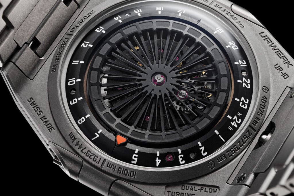 Vis&atilde;o detalhada da parte de tr&aacute;s de um rel&oacute;gio de luxo com mecanismo mec&acirc;nico exposto, incluindo um design em espiral e elementos t&eacute;cnicos sofisticados. O mostrador possui marca&ccedil;&otilde;es e a inscri&ccedil;&atilde;o "DUAL-FLOW TURBINE".