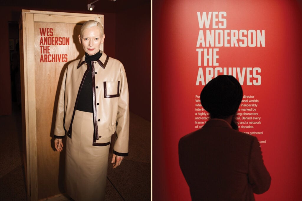 Duas fotografias lado a lado numa exposi&ccedil;&atilde;o: uma pessoa em frente a um painel de madeira com o t&iacute;tulo &ldquo;Wes Anderson: The Archives&rdquo; e outra pessoa a observar um painel vermelho com o mesmo t&iacute;tulo.