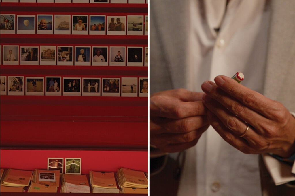 Expositor vermelho com fotografias tipo Polaroid organizadas em filas e, ao lado, m&atilde;os de uma pessoa a segurar um pequeno objecto colorido.