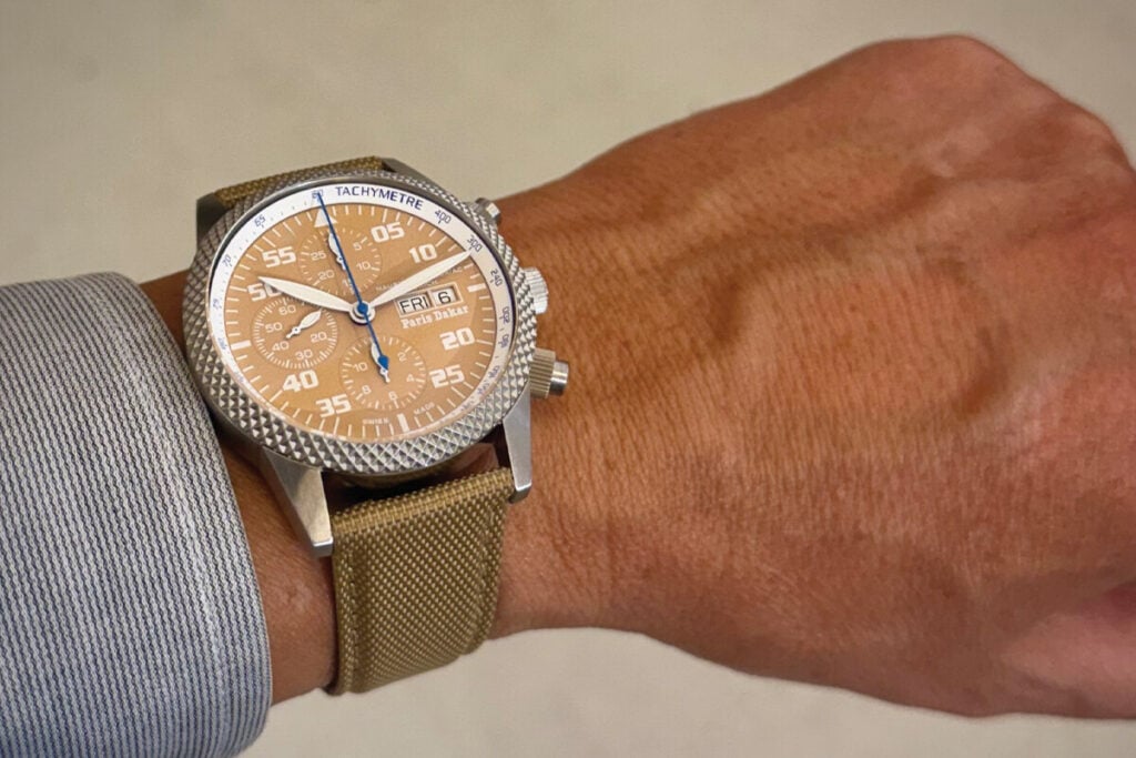 Relógio cronógrafo Maurice de Mauriac com mostrador bege “Paris-Dakar”, escala taquimétrica e bracelete dourada no pulso. Foto: Miguel Seabra