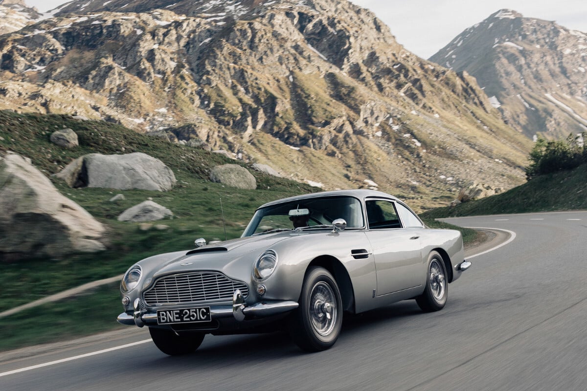 carro Aston Martin DB5 1 em estrada montanhosa Breitling Top Time B01 Chronograph 41 Tribute to Aston Martin DB5 1 | Foto: Breitling